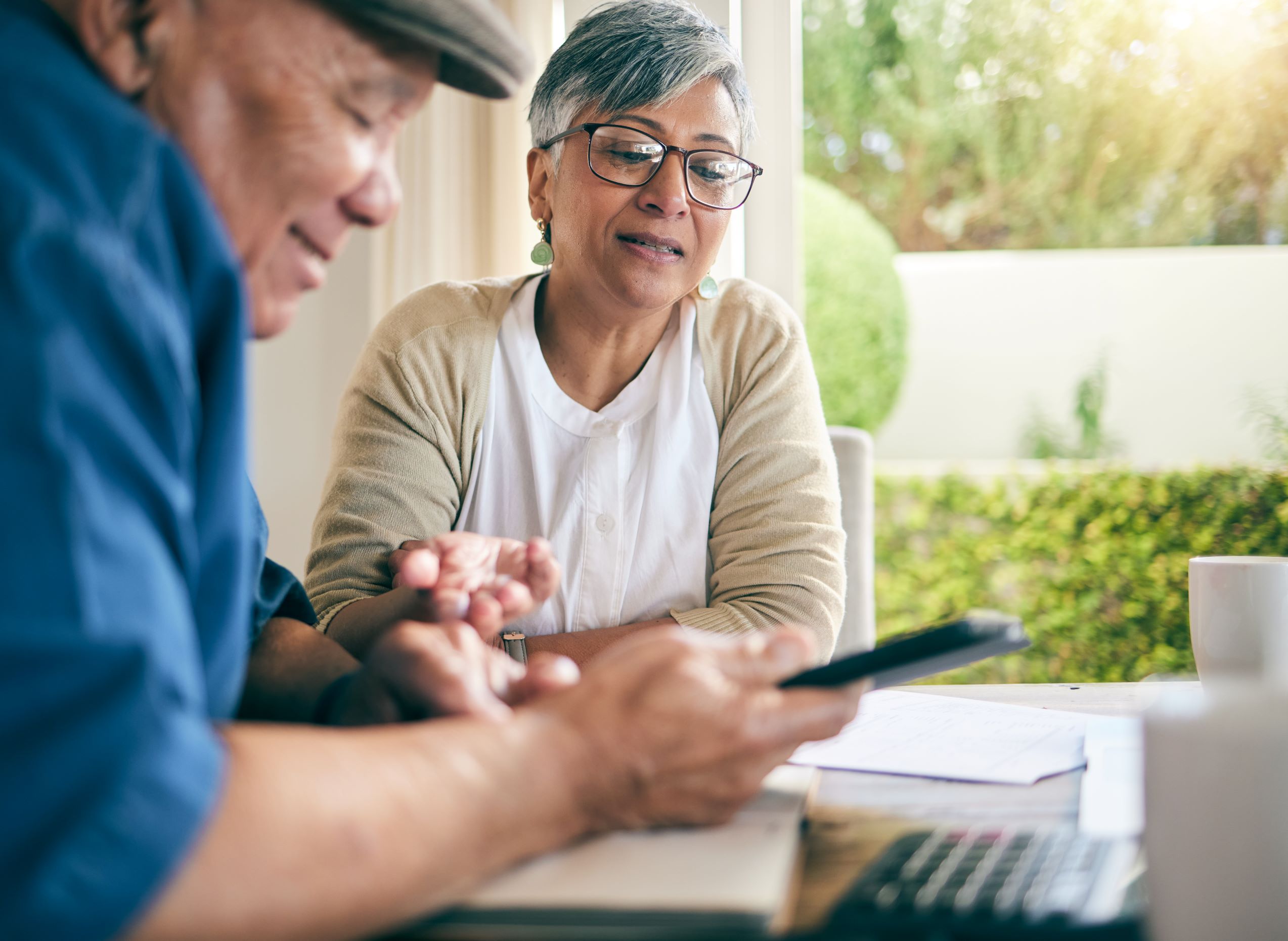 Senior couple sits at table looking through tax paperwork and financial documents.